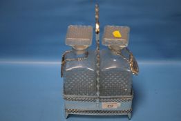 TWO CUT GLASS DECANTERS IN A WHITE METAL STAND