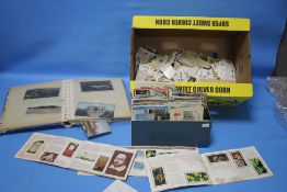 AN ALBUM OF POSTCARDS, along with a tin of loose cards and a selection of tea cards.