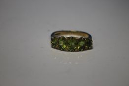 A 9 CT GOLD RING SET WITH FIVE GREEN STONES