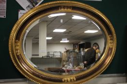 AN OVAL FRAMED MIRROR 85 X 65 CM