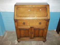A MID CENTURY OAK WRITING BUREAU WITH LEATHER INLAY ON BUN FEET