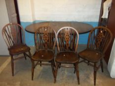 AN ANTIQUE DROP LEAF OAK DINING TABLE AND FOUR WHEEL BACKED CHAIRS