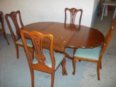 A REPRODUCTION DROP LEAF PEDESTAL DINING TABLE WITH FOUR CHAIRS WITH CABRIOLE LEGS