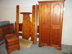 A SOLID PINE DUCAL WARDROBE AND A DOUBLE PINE BED FRAME, TOGETHER WITH A BEDSIDE CUPBOARD