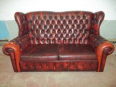 A THREE SEATER VINTAGE OXBLOOD LEATHER WINGED BACK CHESTERFIELD STYLE SOFA