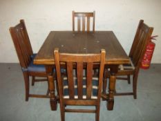 AN EARLY 1900S DRAW LEAF OAK DINING TABLE WITH FOUR CHAIRS