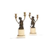 A pair of patinated and parcel gilt bronze and white marble mounted twin light candelabra after the