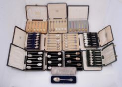 A collection of twelve cased sets of silver and silver coloured spoons