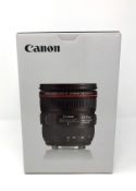 A boxed as new Canon EF 24-70 mm f/4L IS USM lens with lens case and lens hood.