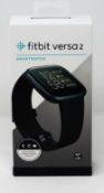 A boxed as new Fitbit Versa 2 Smart Watch in Carbon Aluminium with Classic Black Band (Box sealed).