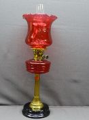 RUBY RED & BRASS VICTORIAN OIL LAMP with black pot base, reeded brass column with ruby font and
