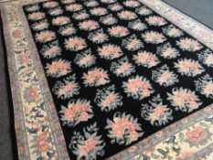 LARGE CHINESE WOOLEN RUG in black ground with pink floral decoration and cream floral decorated