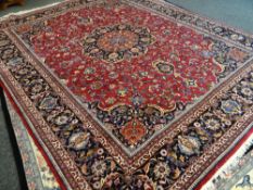 LARGE IRANIAN WOOLEN RUG mainly red ground with central decoration and contrasting border, 378 x