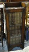 VINTAGE NARROW SINGLE GLAZED DOOR BOOKCASE with rail-top and containing a suite of vintage