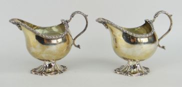 PAIR OF LATE VICTORIAN SILVER CREAM JUGS raised on scroll design pedestal with loop handle and