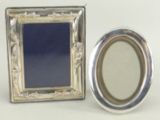 TWO MODERN SILVER PHOTOGRAPH FRAMES, plain oval and embossed rectangular, largest 13cms high (2)