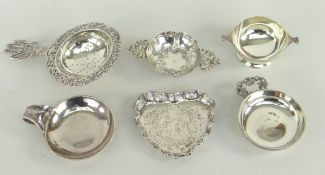 SIX SMALL SILVER COLLECTABLES comprising three wine tasters, a tea strainer, a miniature quaich