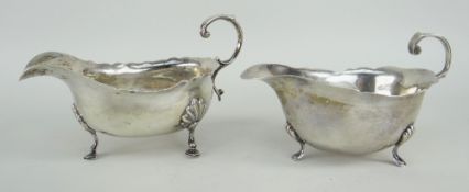 TWO SIMILAR SILVER SAUCE BOATS raised on three feet with scroll handles, Chester and London