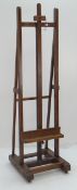 GOOD OAK PICTURE EASEL with adjustable support on casters, 210cms high
