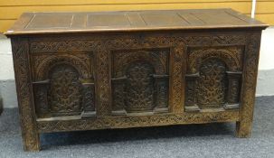 LATE 17TH CENTURY CARVED OAK COFFER of four panelled hinge top, above a heavily carved triple arched