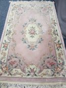WASHED WOOLLEN CHINESE CARPET, pink and cream ground with central floral motif and bordered edge,