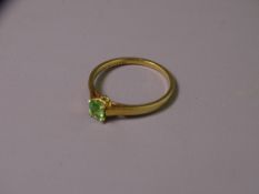 18CT GOLD TSAVORITE DRESS RING having an oval faceted solitaire, 5 x 4mms, moderate olive green