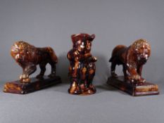 VICTORIAN TREACLE GLAZE STANDING LIONS, a pair, modelled as opposing figures standing with a paw
