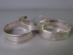 THREE SILVER BANGLES to include a 1906 Edwardian with rope edging and a 1975 hinged bangle, 2.2 troy