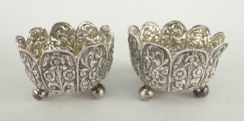 PAIR OF 19TH CENTURY INDIAN KUTCH SILVER FOLIATE SALTS BY OOMERSEE MAWJEE & SONS, on three ball