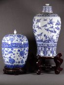 TWO ORIENTAL BLUE & WHITE STORAGE JARS on carved hardwood stands decorated with peonies and a