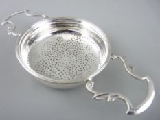 SILVER LEMON STRAINER with twin leaf form handles and star pattern pierced base of Georgian style,