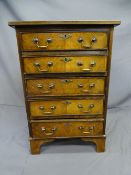 WALNUT REPRODUCTION CHEST of 5 drawers with brass swan-neck handles and on bracket supports, 50cms
