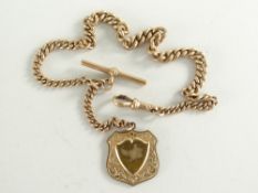 9CT GOLD GRADUATED WATCH CHAIN WITH 'T' BAR and plated engraved shield design pendant. 29.3gms