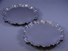 SILVER SALVERS, a pair, each of plain form with wavy rims on 3 scrolled feet, 25cms diameter, 36ozs,