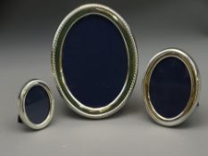 SET OF THREE MATCHING SILVER PHOTO FRAMES of oval form and graduated size (largest 16cms),1988