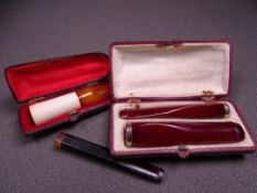 PAIR OF CASED AMBER COLOURED CIGAR & CIGARETTE HOLDERS, possibly gold banded, another amber coloured