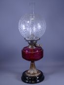 BRASS BASED OIL LAMP having a Cranberry glass reservoir and an etched floral bowl shade
