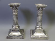 PAIR OF SILVER CANDLESTICKS, square based classical decoration with Corinthian columns and shaped