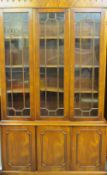 A REPRODUCTION BOOKCASE CUPBOARD with triple astragal glazed doors above three panelled cupboard