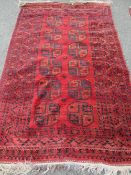 INDIAN RED GROUND WOOLLEN CARPET having a central repeating block pattern and a multi-bordered