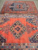 TWO VINTAGE EASTERN WOOLLEN RUGS, red ground with traditional pattern centres and multiple