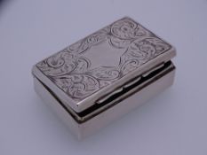 SILVER LIDDED PILL OR MATCHBOX, oblong with floral scrolled lid and scrolled base with centre