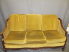 WALNUT FRAMED BERGERE THREE SEATER SETTEE with carved knuckle detail to the arm ends on ball and