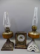 TWO VINTAGE GLASS FONT OIL LAMPS on cast iron bases and a wooden cased mantel clock