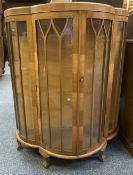 WALNUT BOW FRONT CHINA DISPLAY CABINET having twin central opening doors and glazed side panels on