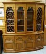 MODERN GOLDEN OAK ANGLED CABINET, four glazed upper doors above foliate carved paneled cupboard