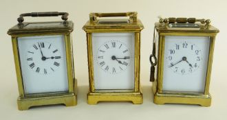 THREE SIMILAR BRASS CARRIAGE CLOCKS all with swing handles and enamel faces one being a presentation