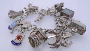 SILVER CHARM BRACELET with padlock clasp and 15 various charms including a £1 note in emergency