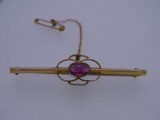 A 9CT GOLD BAR BROOCH with centre oval garnet, 2.2grms