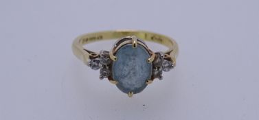 AN 18CT GOLD DRESS RING with a cluster of oval blue quartz and three tiny flanking diamonds either
